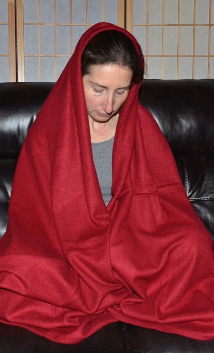 Empar is cloaked in a deep red Gesar meditation shawl, equally appropriate as a travel blanket