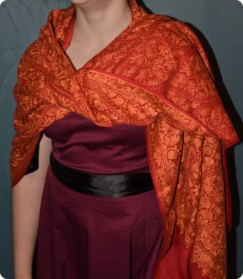 Liana is wearing a sumptuous shawl embroidered in orange and red on ultra-fine wool by the master artisans at Local Womens Handicrafts in Kathmandu, Nepal